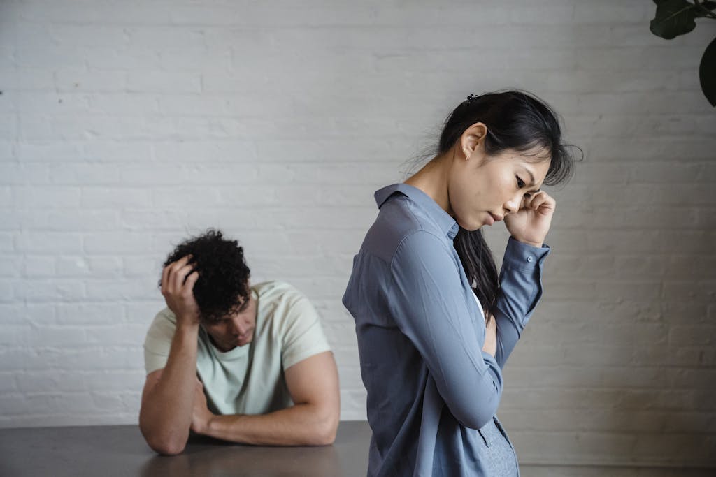 An Asian woman and man feeling misunderstood and frustrated in a relationship indoors.